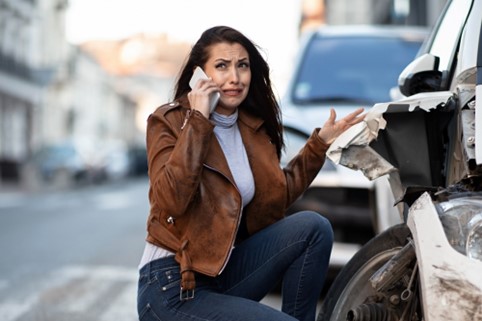 Woman cries on the phone after having a car accident.