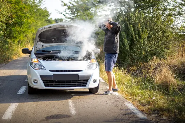 Man looks at the smoke emitting from his vehicle engine