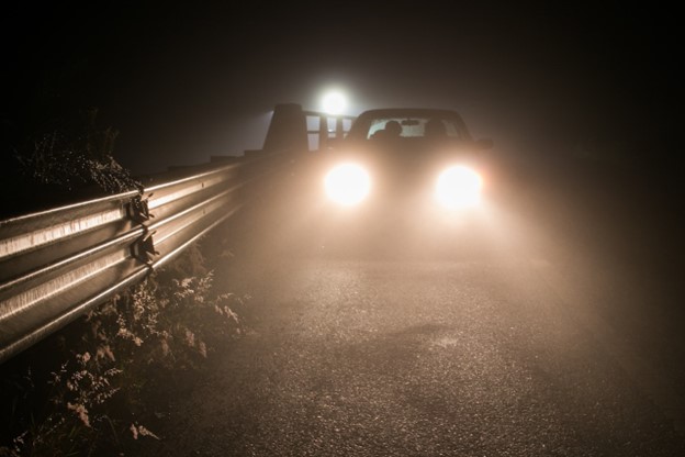 Car parked at the side of the road at night with headlights on