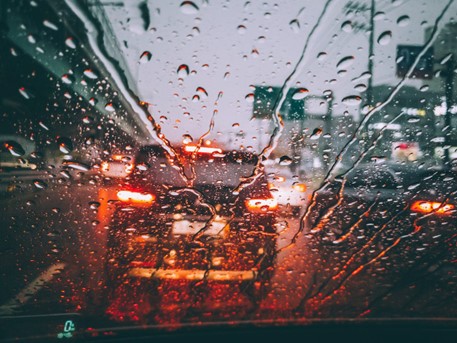 Car break lights shining through rain spluttered windscreen