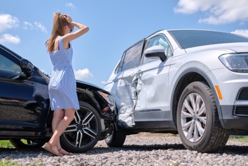 Woman looks at accident-damage incurred on car